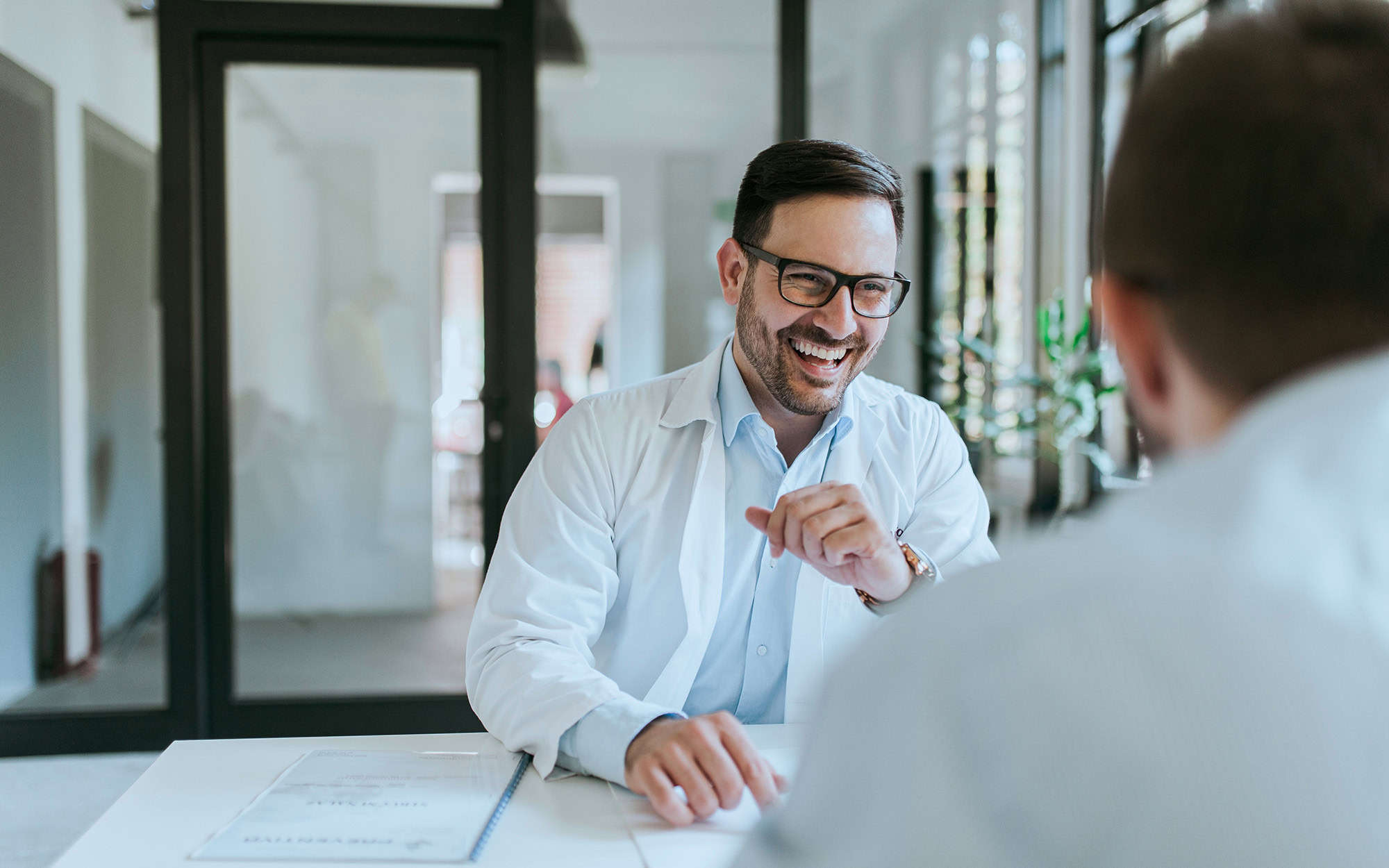 Front View Of Smiling Jovial Man Talking To Colleague