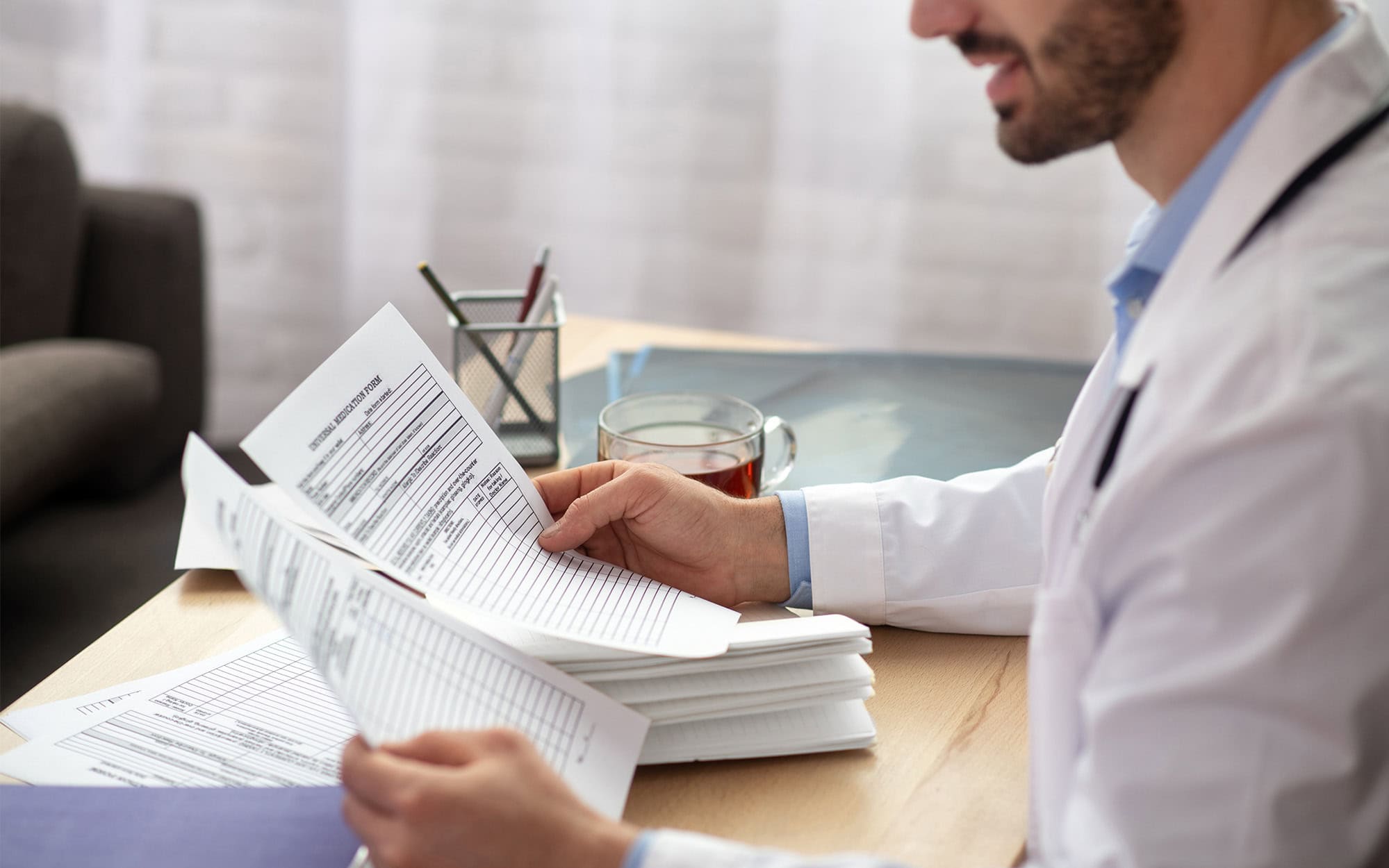 Side View Of Serious Young Doctor Looking At Documents